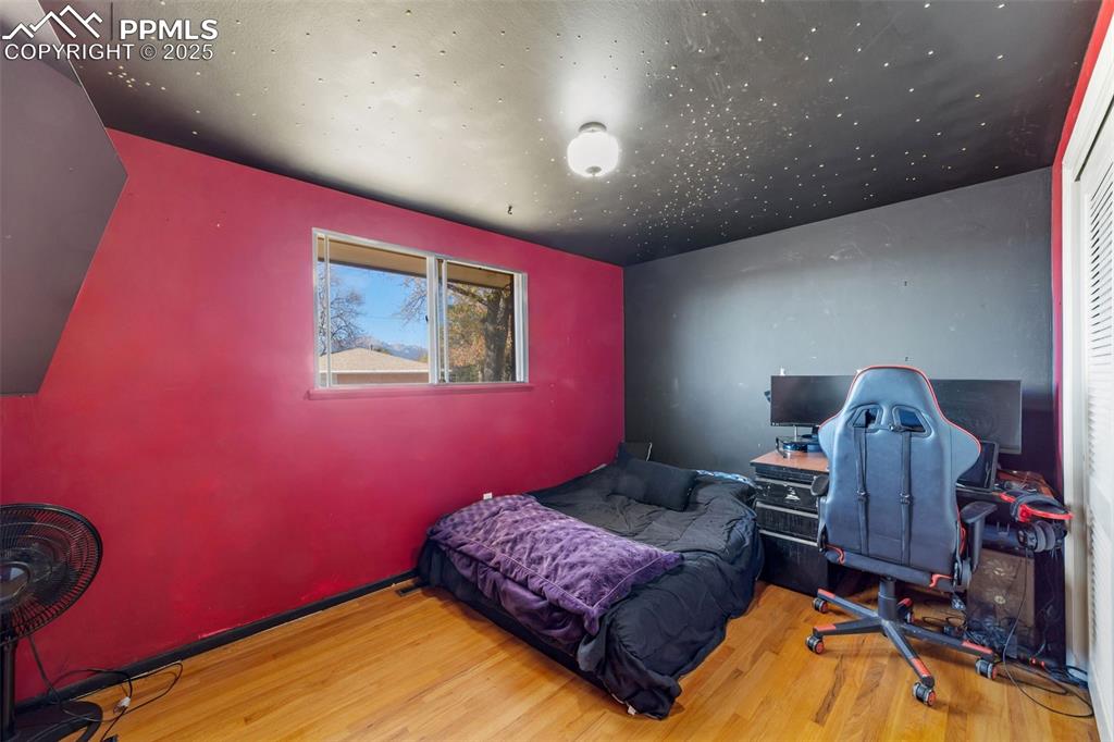 Image 23 of 49: Bedroom with wood finished floors and a desk