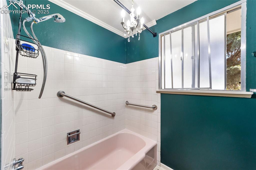 Image 26 of 49: Full bath with shower combination, ornamental molding, and a chandelier