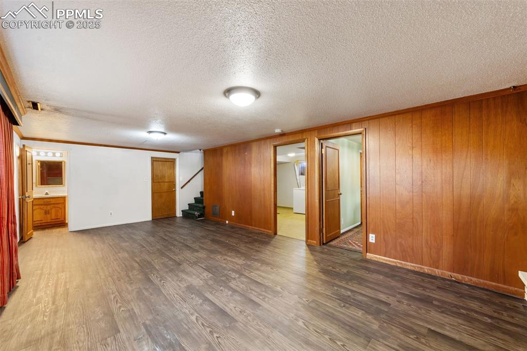 Image 29 of 49: Unfurnished room with ornamental molding, stairway, dark wood finished floo