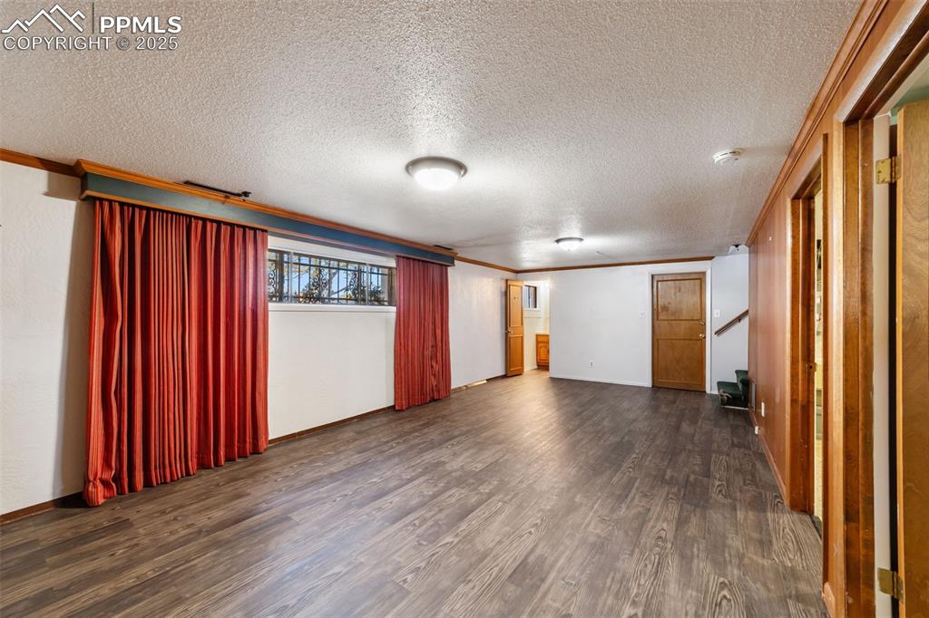 Image 30 of 49: Spare room with dark wood-style flooring, a textured ceiling, crown molding