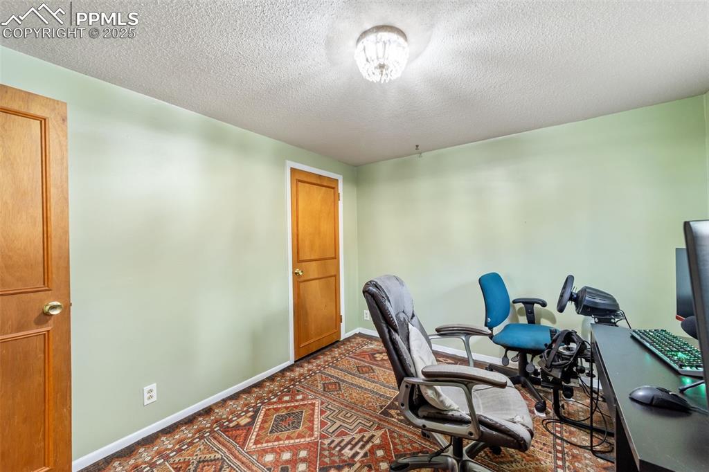 Image 33 of 49: Office area with a textured ceiling and baseboards