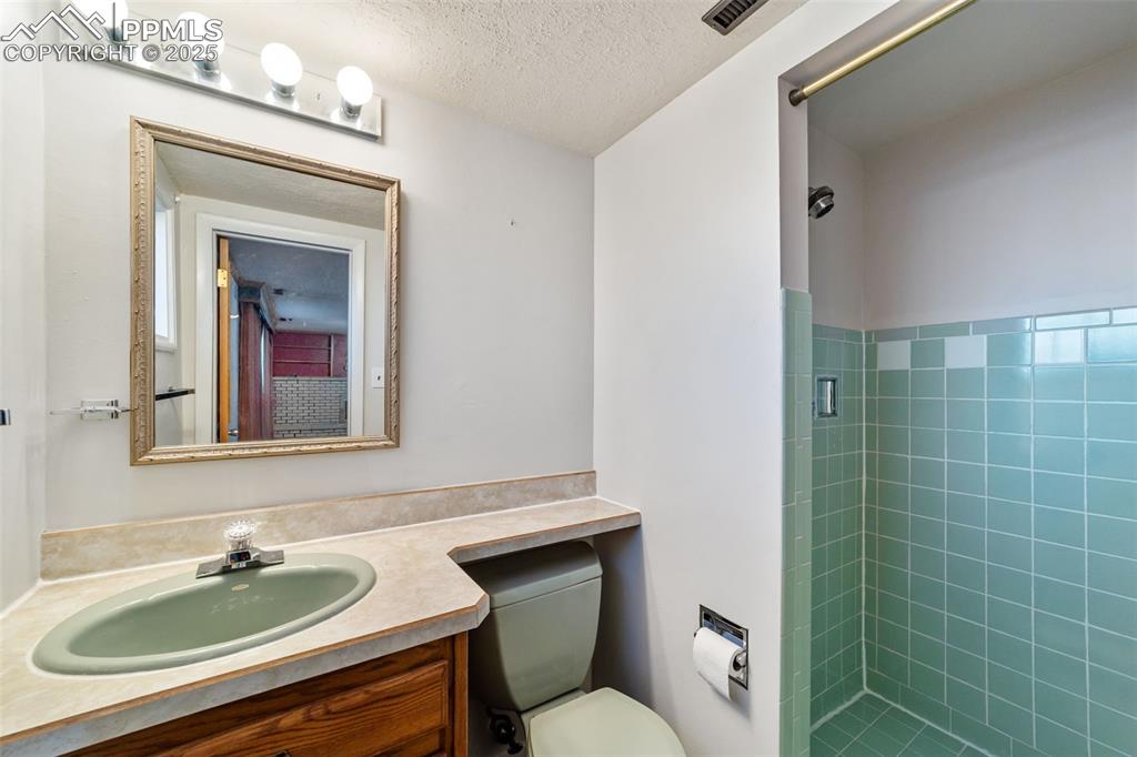 Image 34 of 49: Bathroom with a stall shower, vanity, and a textured ceiling