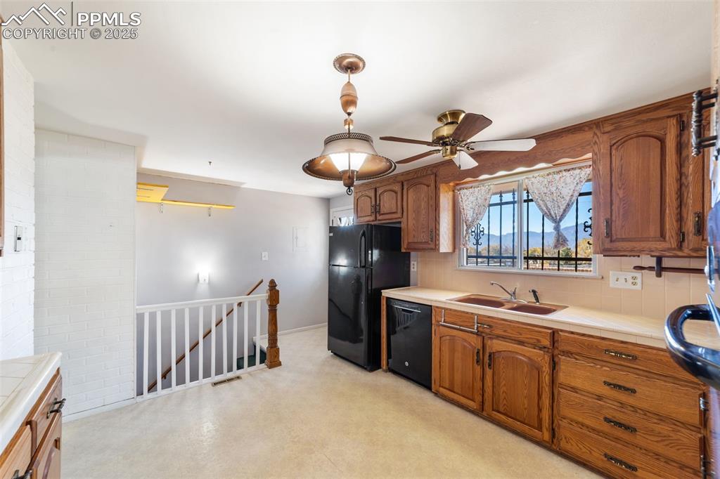 Image 4 of 49: Kitchen featuring brown cabinets, backsplash, tile counters, black dishwash