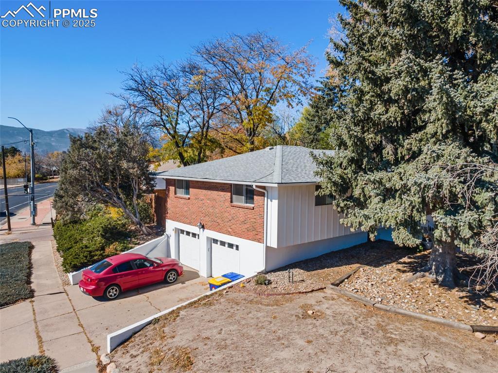 Image 44 of 49: View of side of property featuring driveway, a garage, brick siding, and a