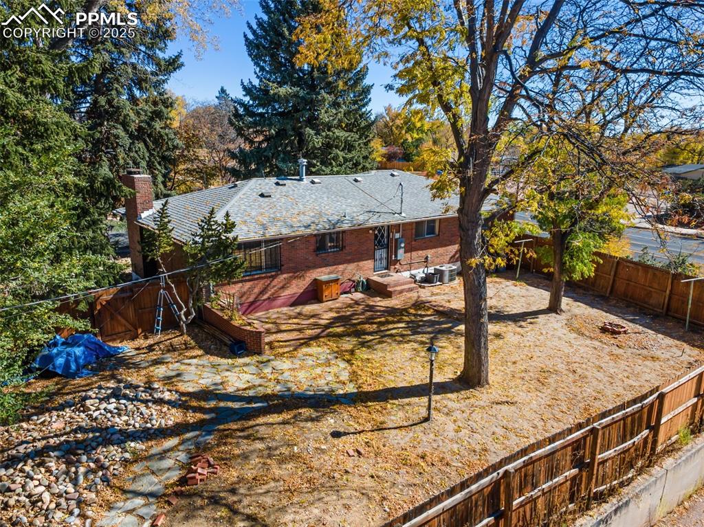 Image 47 of 49: Rear view of property with a fenced backyard, a chimney, and brick siding