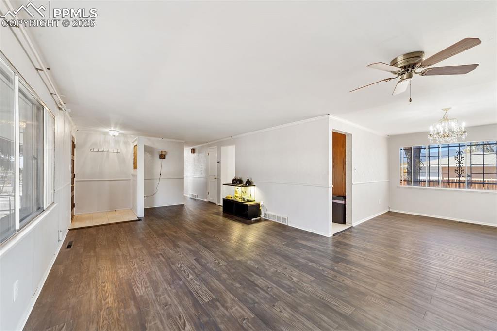 Image 7 of 49: Unfurnished living room featuring dark wood-style flooring, a chandelier, a