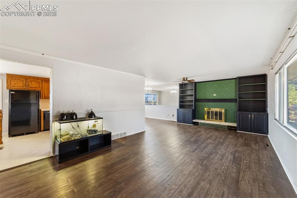 Image 8 of 49: Living area featuring dark wood-type flooring, a brick fireplace, crown mol