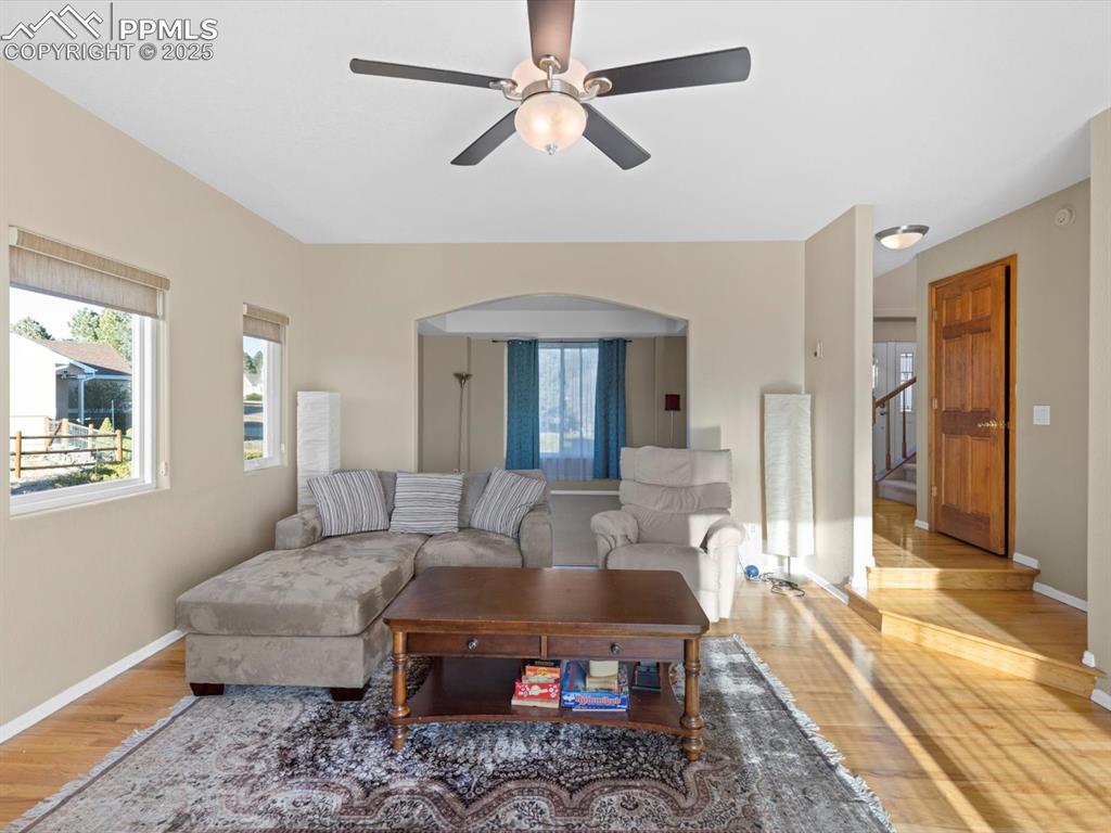 Image 12 of 49: Living room featuring wood finished floors, ceiling fan, and stairs