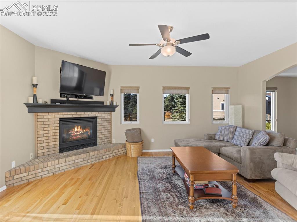 Image 14 of 49: Living room featuring wood finished floors, a brick fireplace, arched walkw