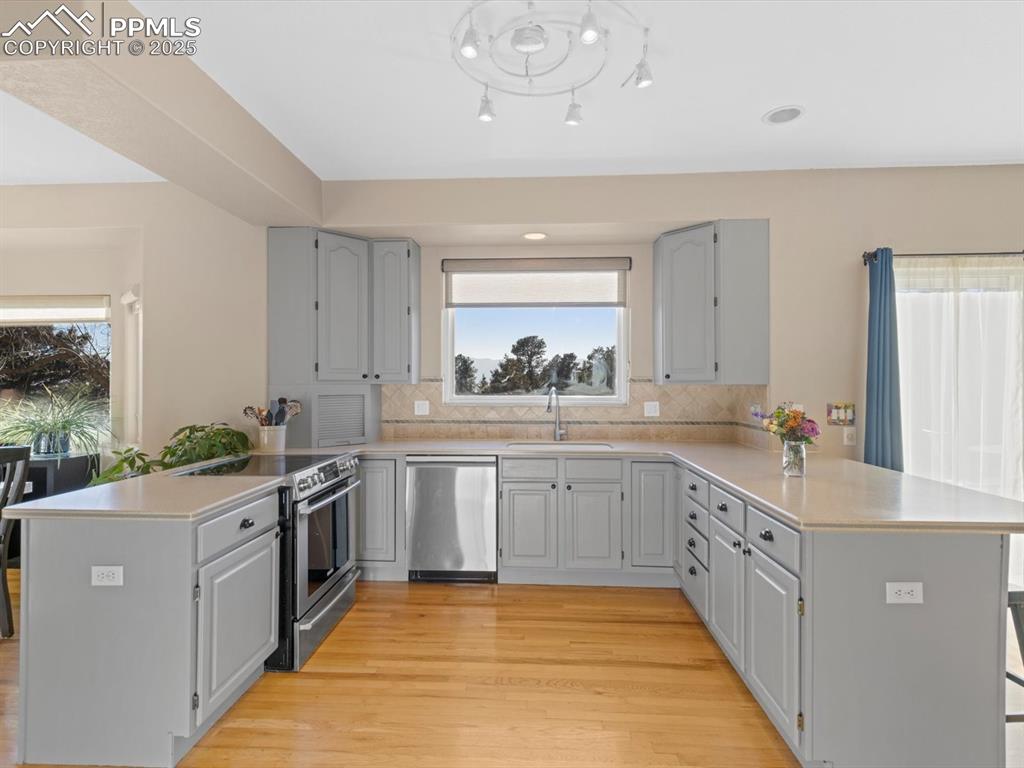 Image 15 of 49: Kitchen with a peninsula, gray cabinets, appliances with stainless steel fi