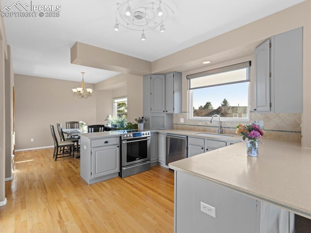 Image 16 of 49: Kitchen featuring a peninsula, gray cabinetry, stainless steel appliances,