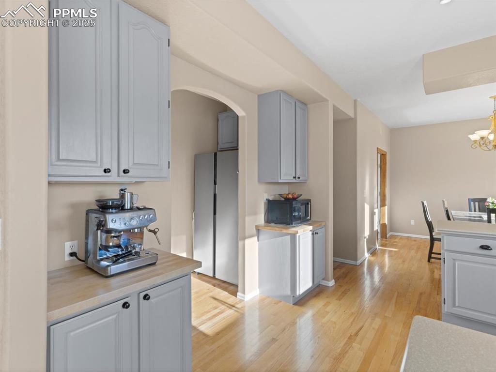 Image 18 of 49: Kitchen with light countertops, light wood-style flooring, arched walkways,