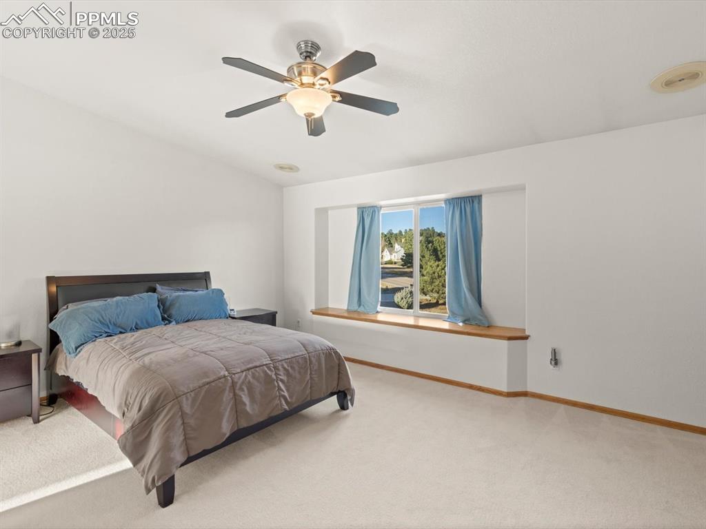Image 23 of 49: Carpeted bedroom with a ceiling fan and baseboards