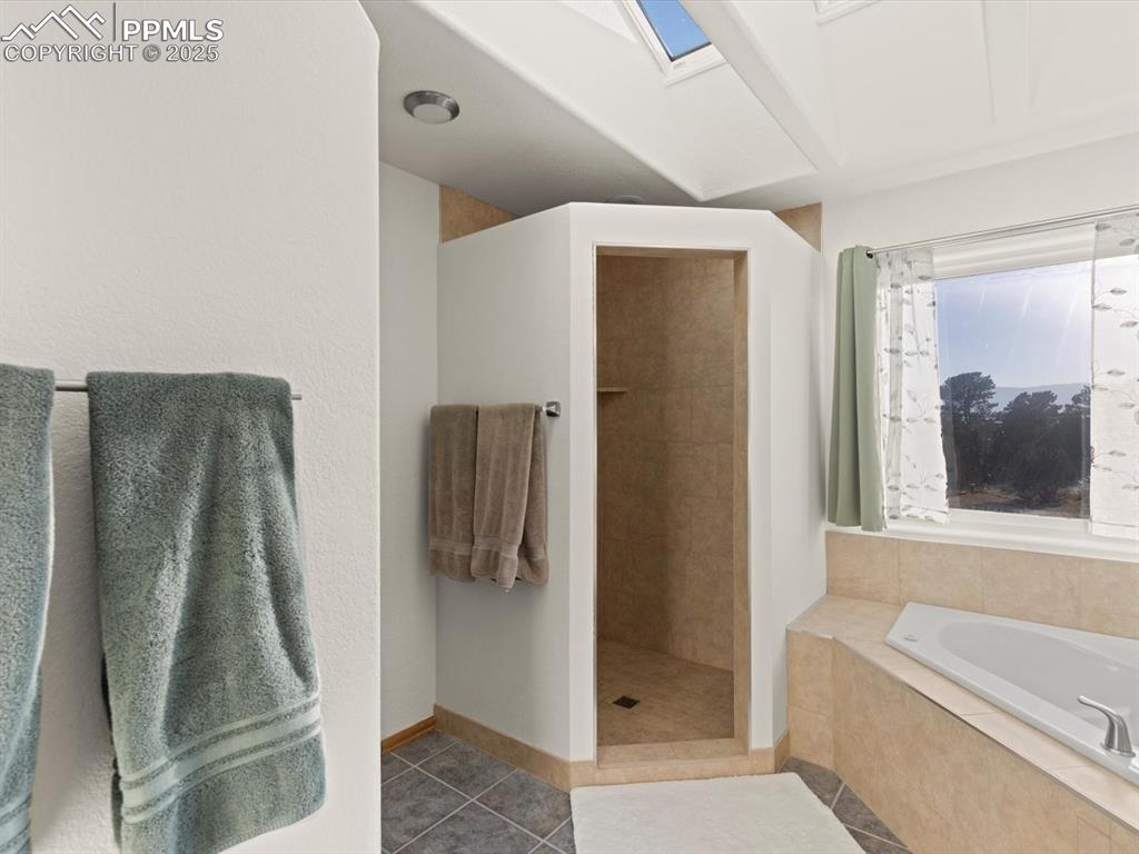 Image 27 of 49: Full bathroom featuring tile patterned flooring, a garden tub, a tile showe