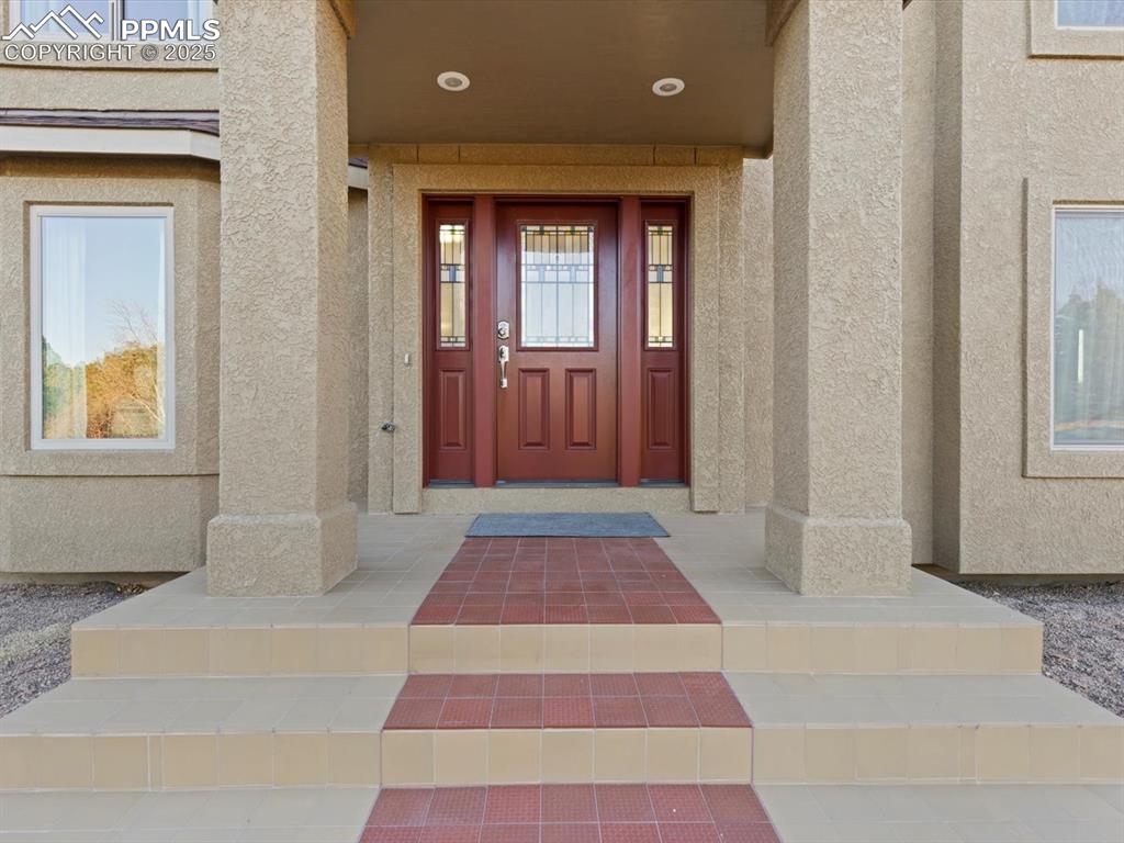 Image 3 of 49: Doorway to property with stucco siding and covered porch