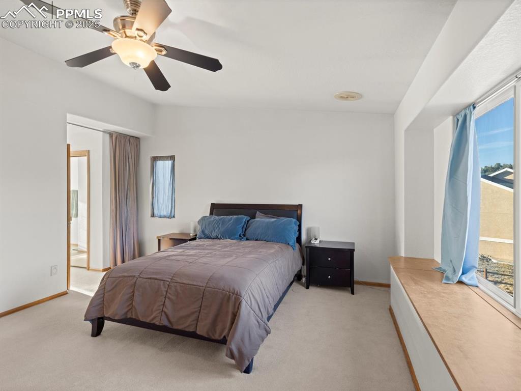 Image 32 of 49: Bedroom featuring light carpet, ceiling fan, ensuite bath, and access to ex