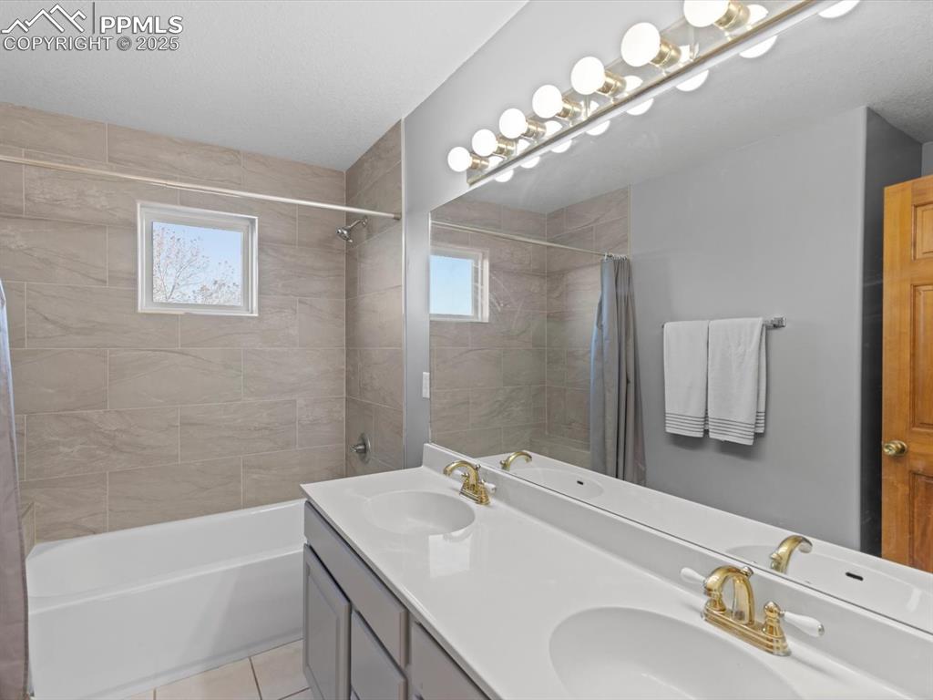 Image 33 of 49: Full bathroom with double vanity, shower / tub combo with curtain, and ligh