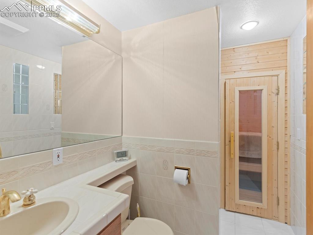 Image 34 of 49: Bathroom featuring tile walls, vanity, a sauna / steam room, and light tile