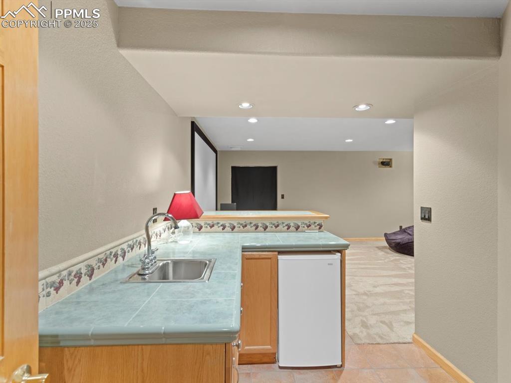 Image 37 of 49: Kitchen featuring a textured wall, a peninsula, white fridge, tile countert