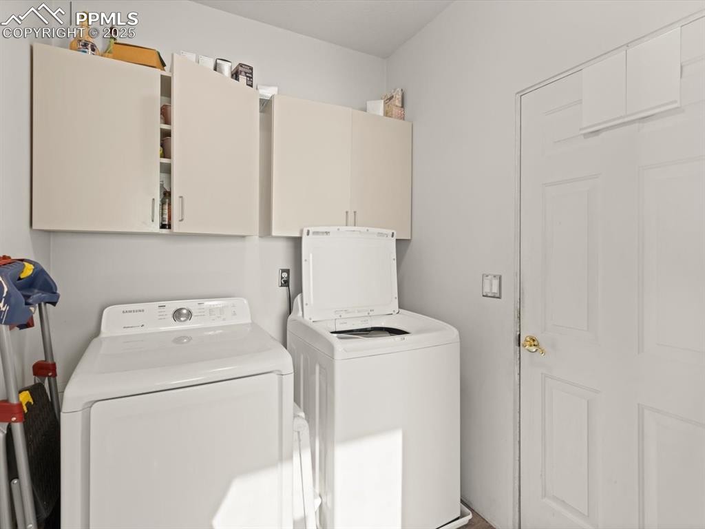 Image 42 of 49: Laundry area featuring washing machine and dryer and cabinet space