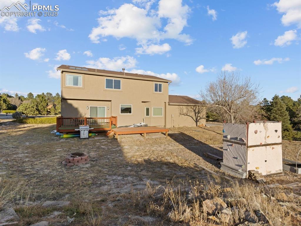 Image 49 of 49: Back of house featuring a deck, stucco siding, and an outdoor fire pit