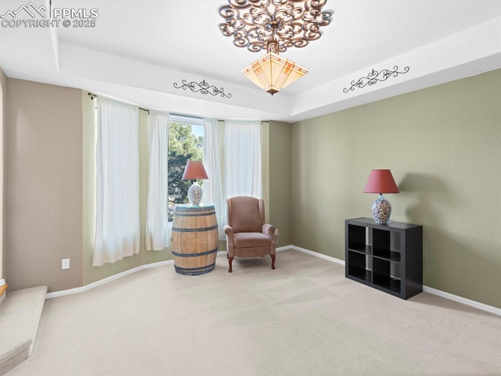 Image 5 of 49: Living area featuring a tray ceiling and carpet flooring