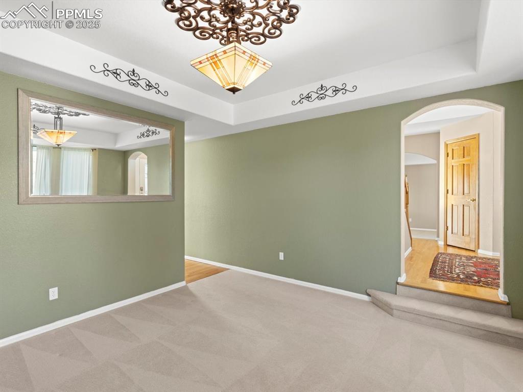 Image 8 of 49: Carpeted spare room featuring a raised ceiling and arched walkways