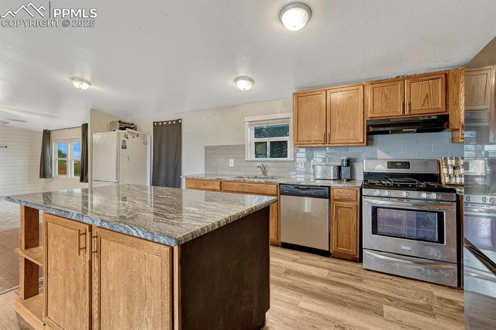 Image 10 of 38: Kitchen featuring appliances with stainless steel finishes, brown cabinets,
