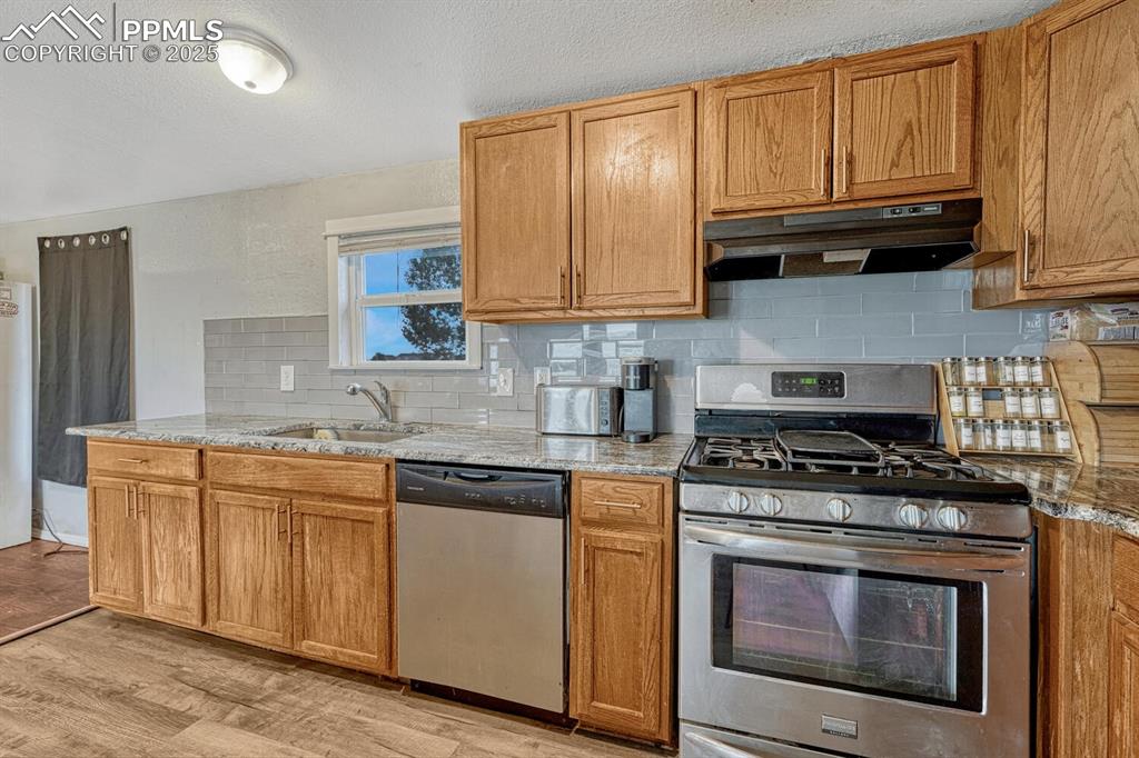 Image 11 of 38: Kitchen with decorative backsplash, stainless steel appliances, brown cabin