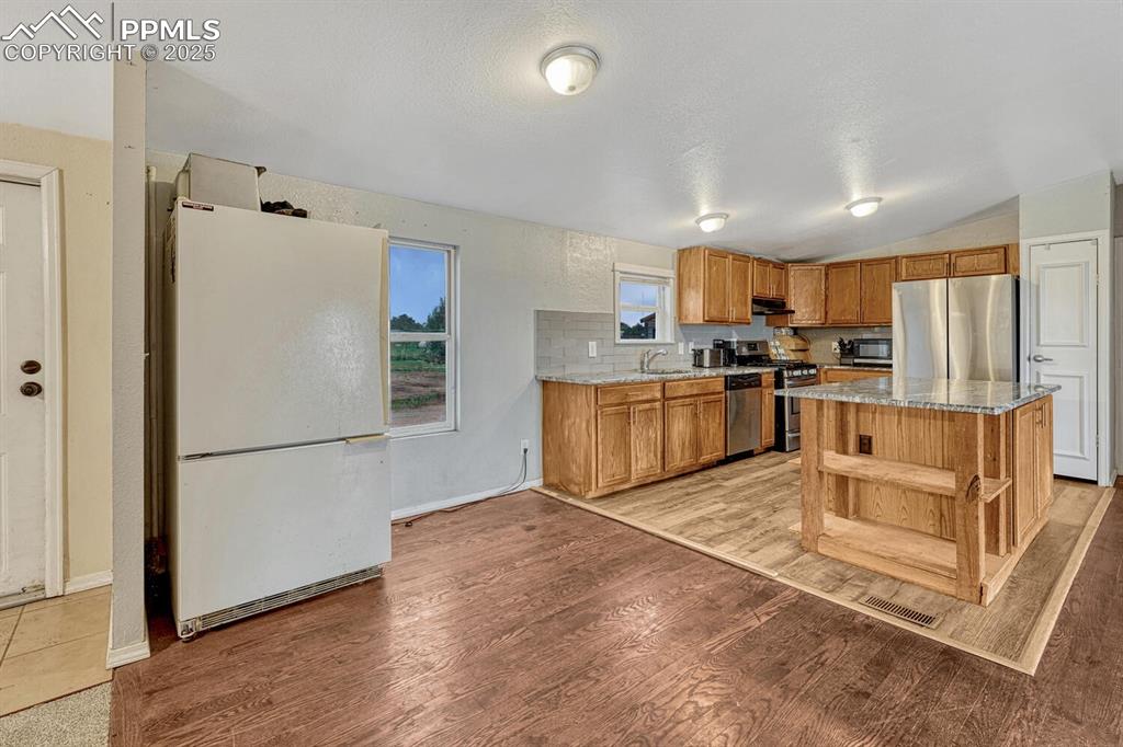 Image 12 of 38: Kitchen featuring appliances with stainless steel finishes, light stone cou