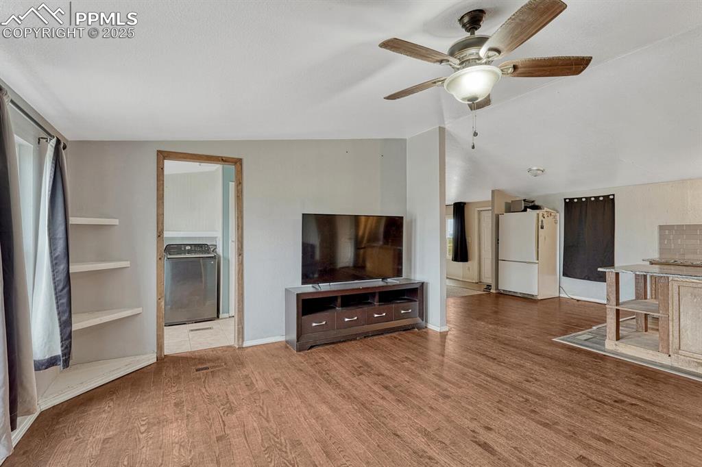Image 14 of 38: Family room with wood finished floors, vaulted ceiling, built in shelves an