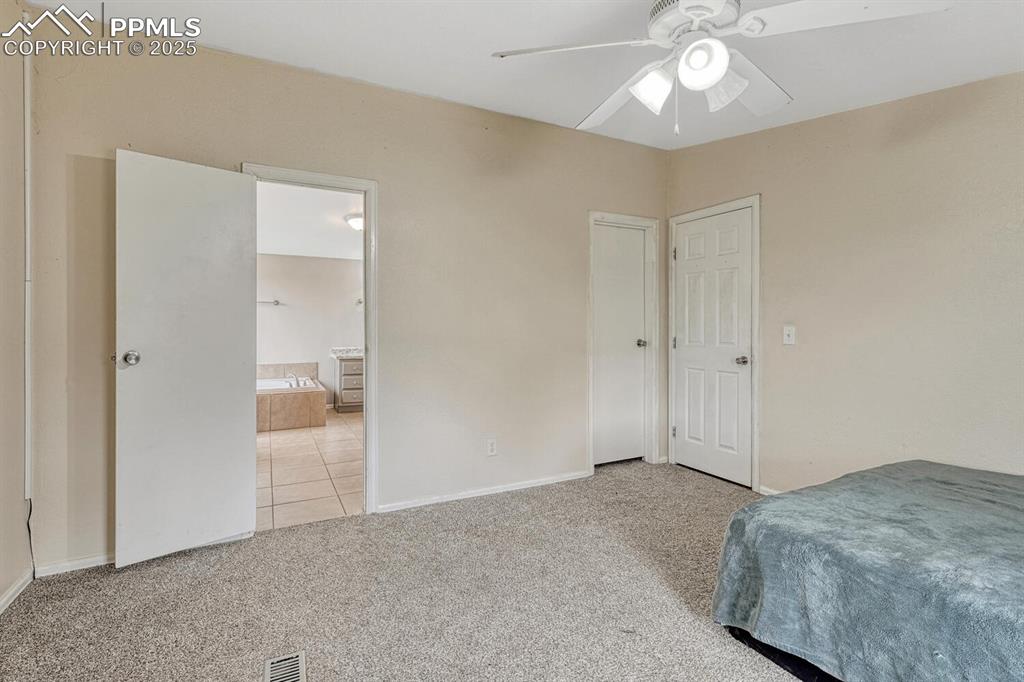 Image 17 of 38: Bedroom featuring light colored carpet, ceiling fan,walk in closet that con