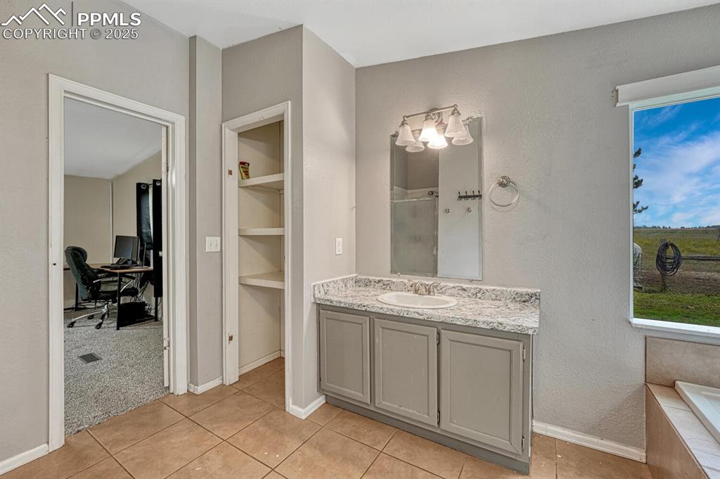 Image 18 of 38: Full bathroom with vanity, light tile patterned floors, linen closet, a sta