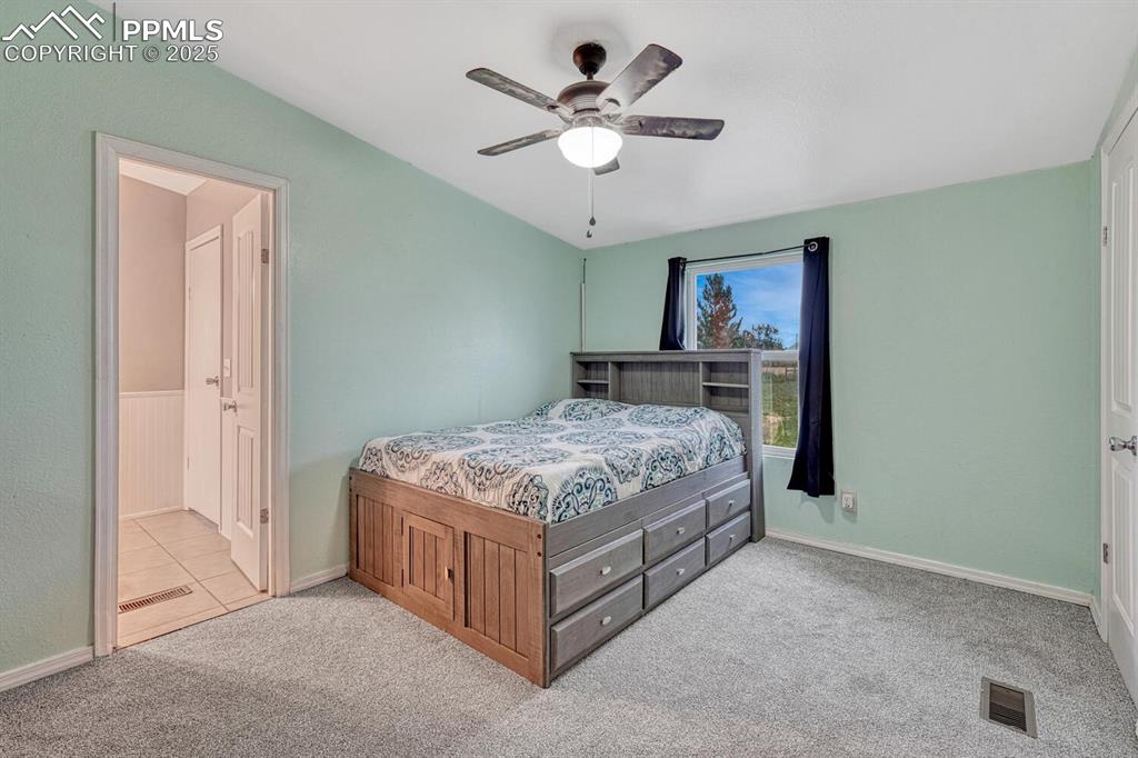 Image 21 of 38: Newely carpeted bedroom with ceiling fan and connects to half bathroom and 