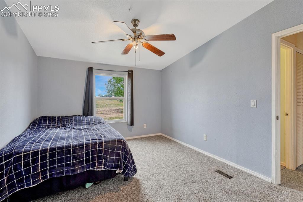 Image 24 of 38: Third bedroom with carpet,ceiling fan and walk-in closet.