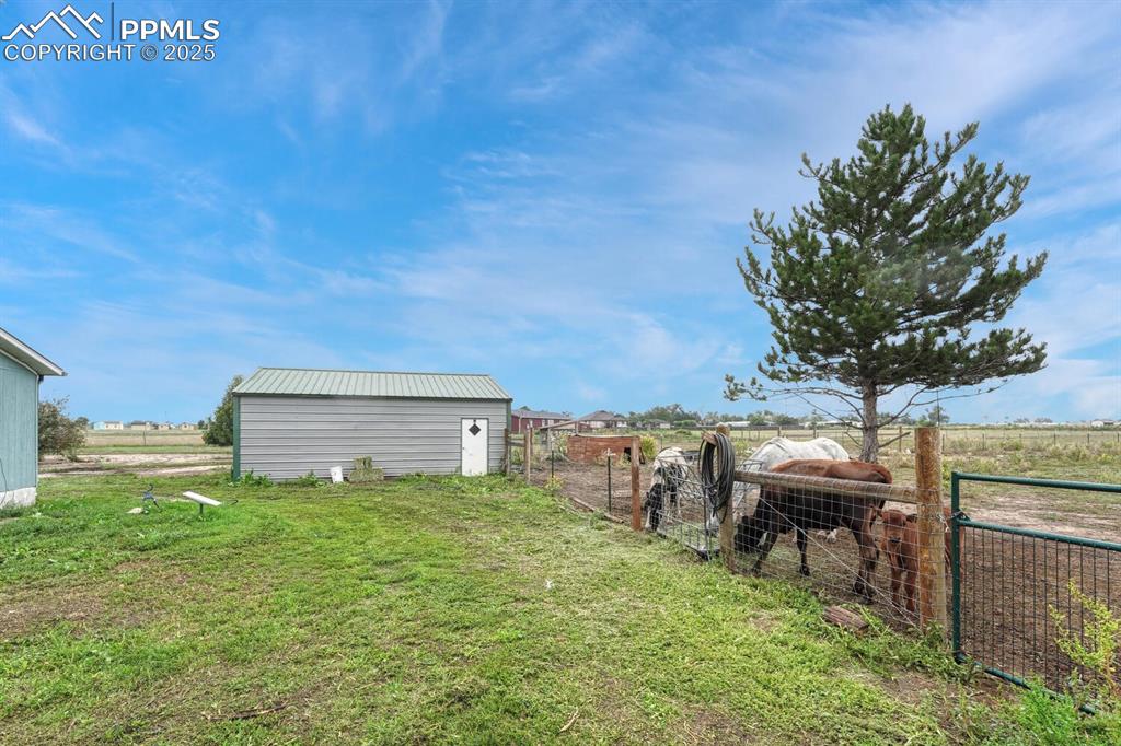 Image 30 of 38: View of yard behind the garage  featuring a view of rural / pastoral area. 