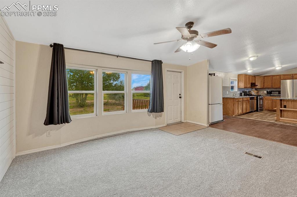 Image 6 of 38: Unfurnished living room featuring plenty of natural light, light colored ca