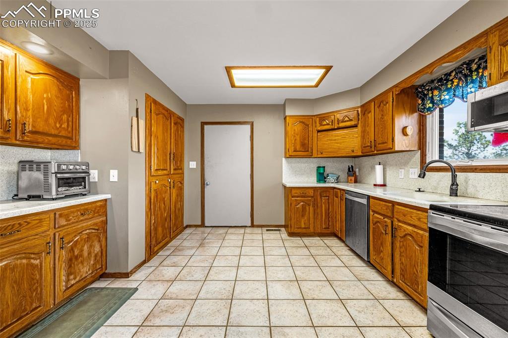 Image 10 of 42: Kitchen with decorative backsplash, stainless steel appliances, brown cabin