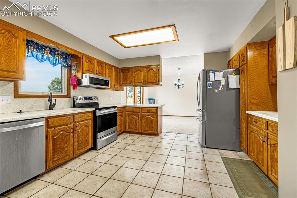 Image 11 of 42: Kitchen featuring brown cabinets, appliances with stainless steel finishes,