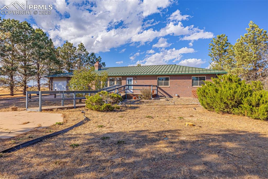 Image 2 of 42: Back of house featuring brick siding, a chimney, a metal roof, and a wooden