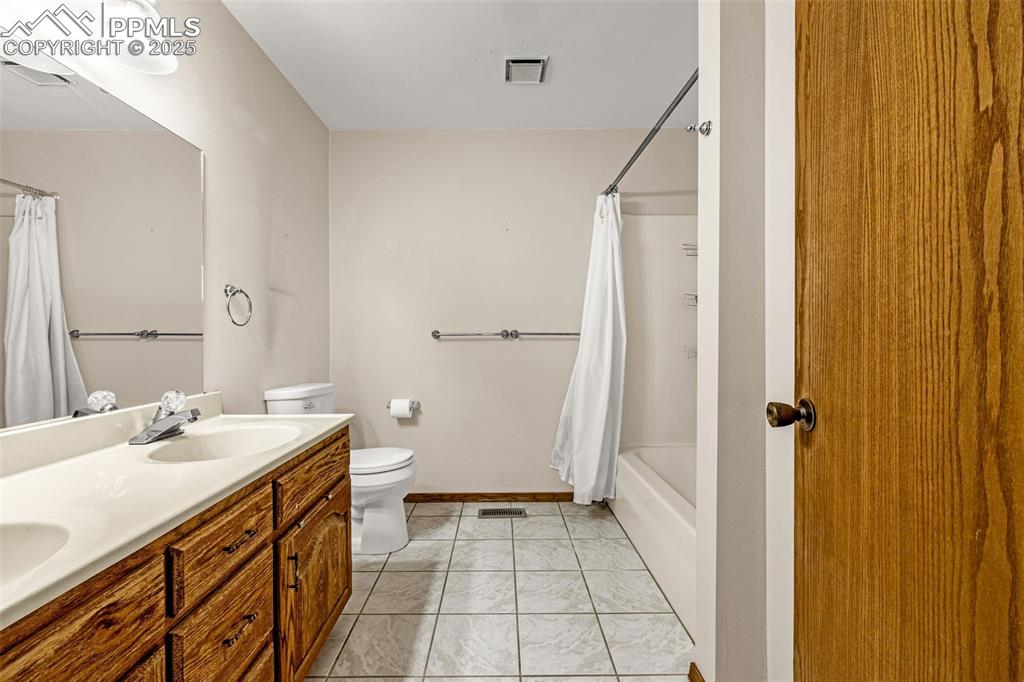 Image 20 of 42: Full bathroom with double vanity, light tile patterned floors, and shower /