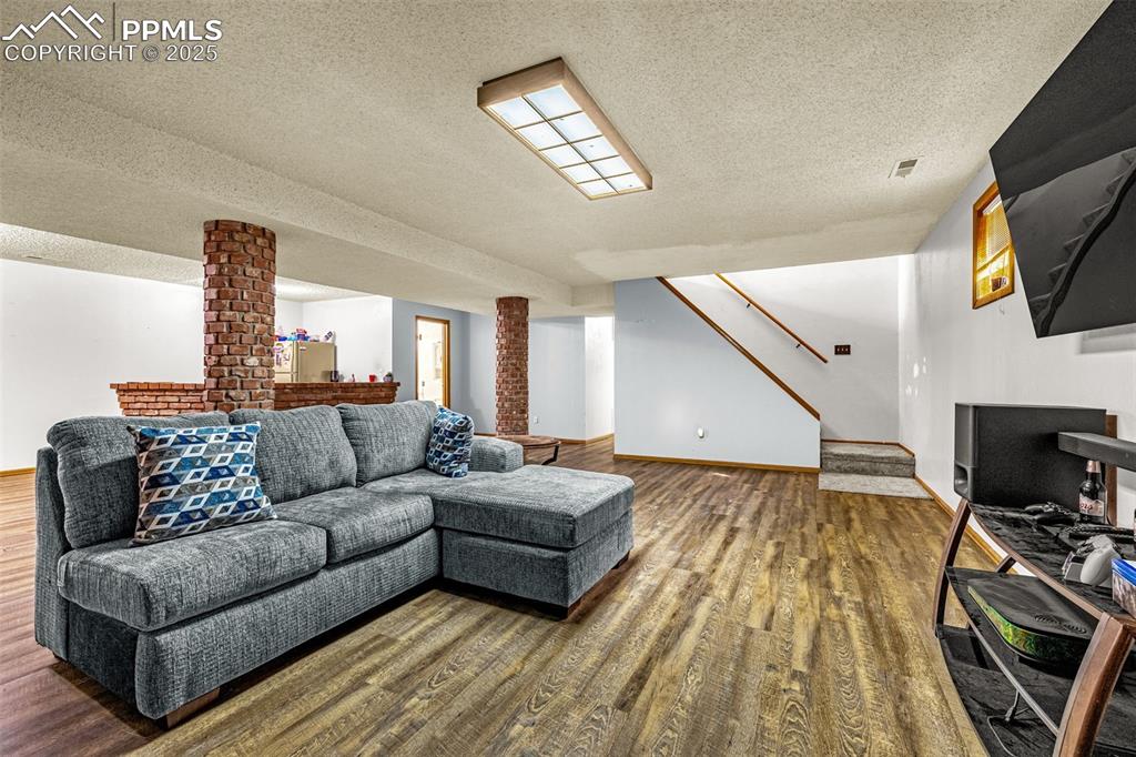 Image 23 of 42: Living room featuring a textured ceiling, wood finished floors, and stairwa