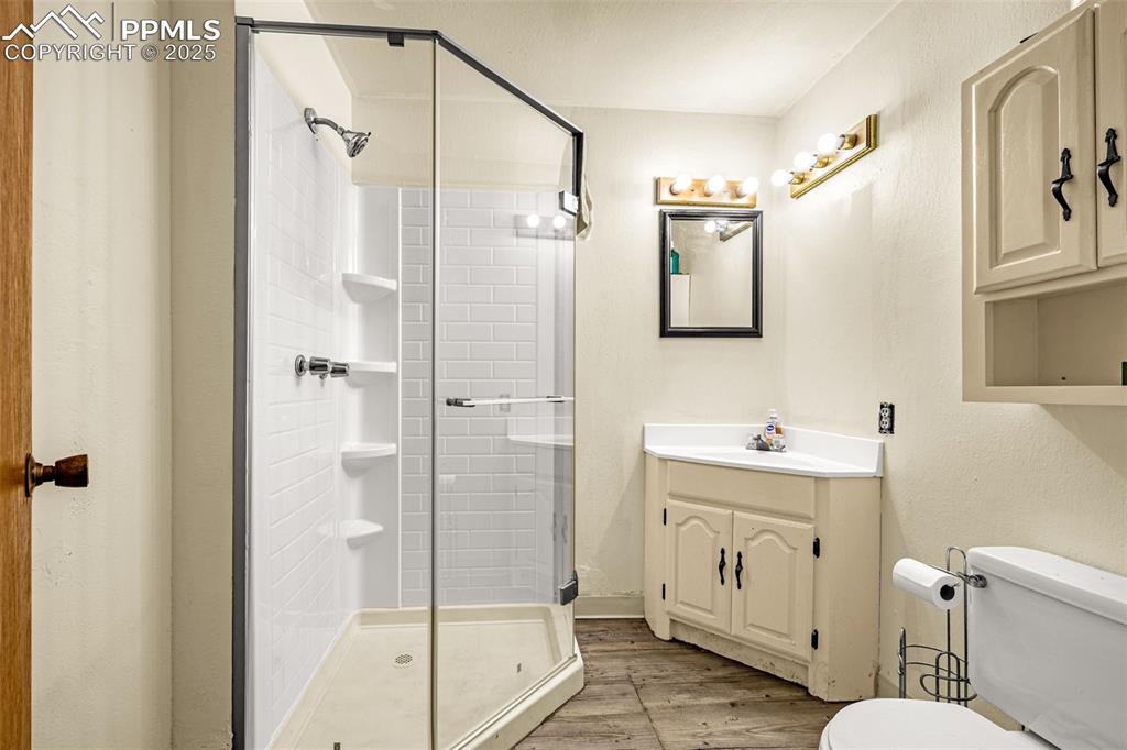 Image 24 of 42: Full bath with light wood-style flooring, vanity, and a stall shower