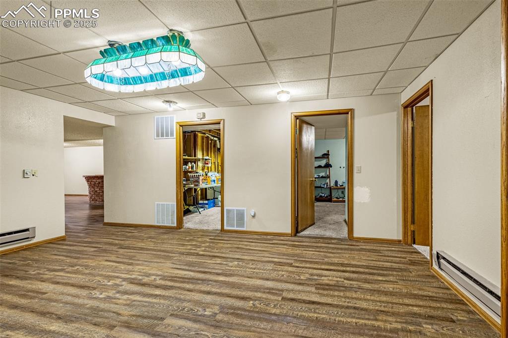 Image 26 of 42: Spare room featuring baseboard heating, wood finished floors, and a paneled
