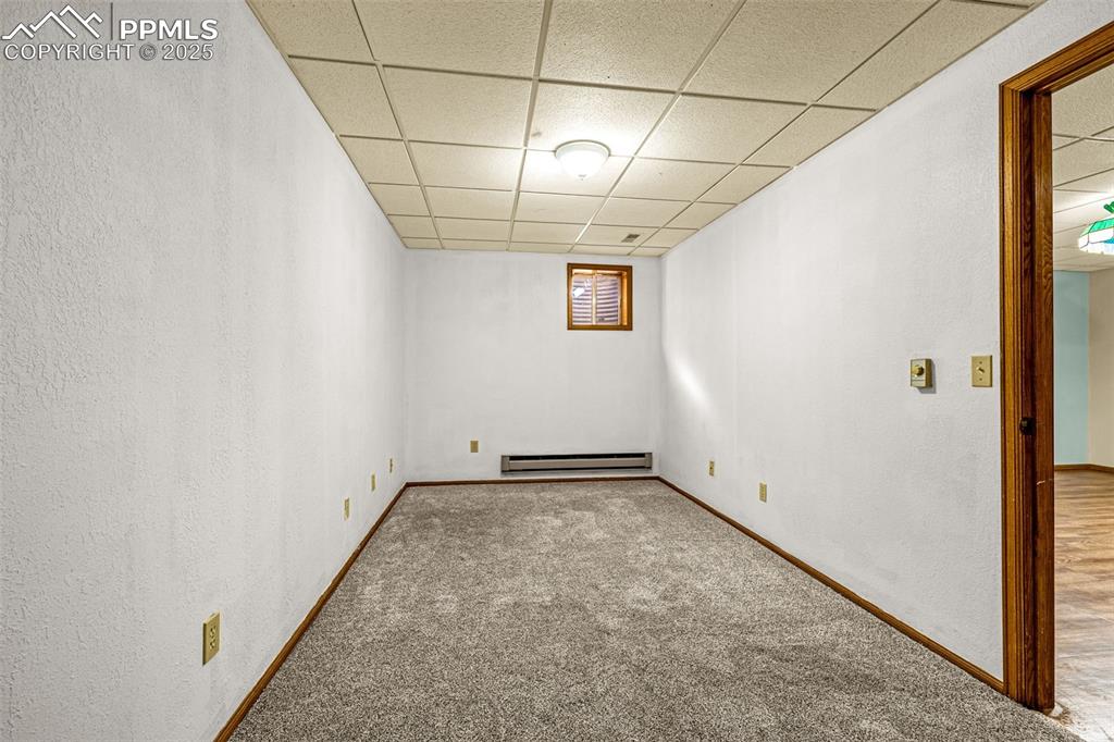 Image 28 of 42: Spare room featuring a drop ceiling, carpet flooring, a textured wall, and 