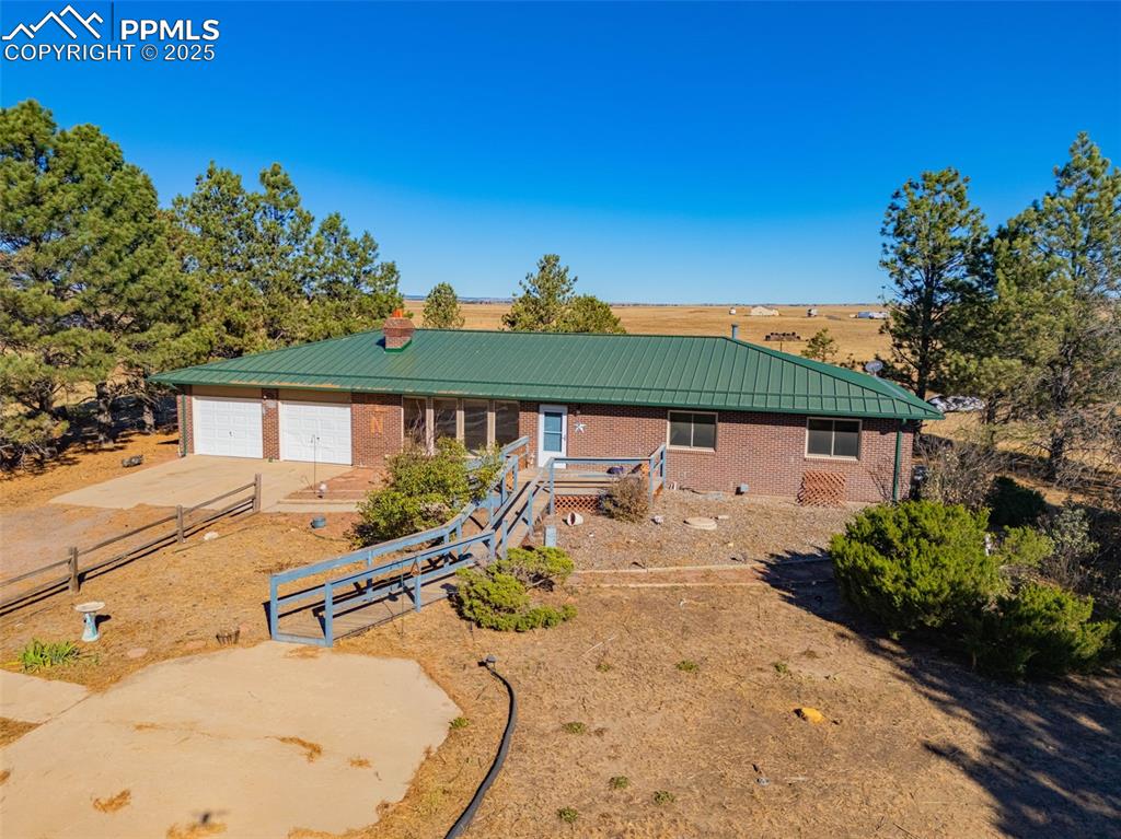 Image 34 of 42: View of front facade featuring a metal roof, driveway, brick siding, a chim