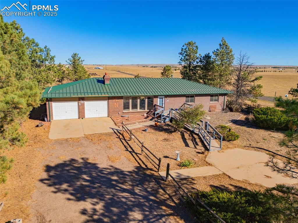 Image 35 of 42: View of front of home with brick siding, a metal roof, driveway, and a view