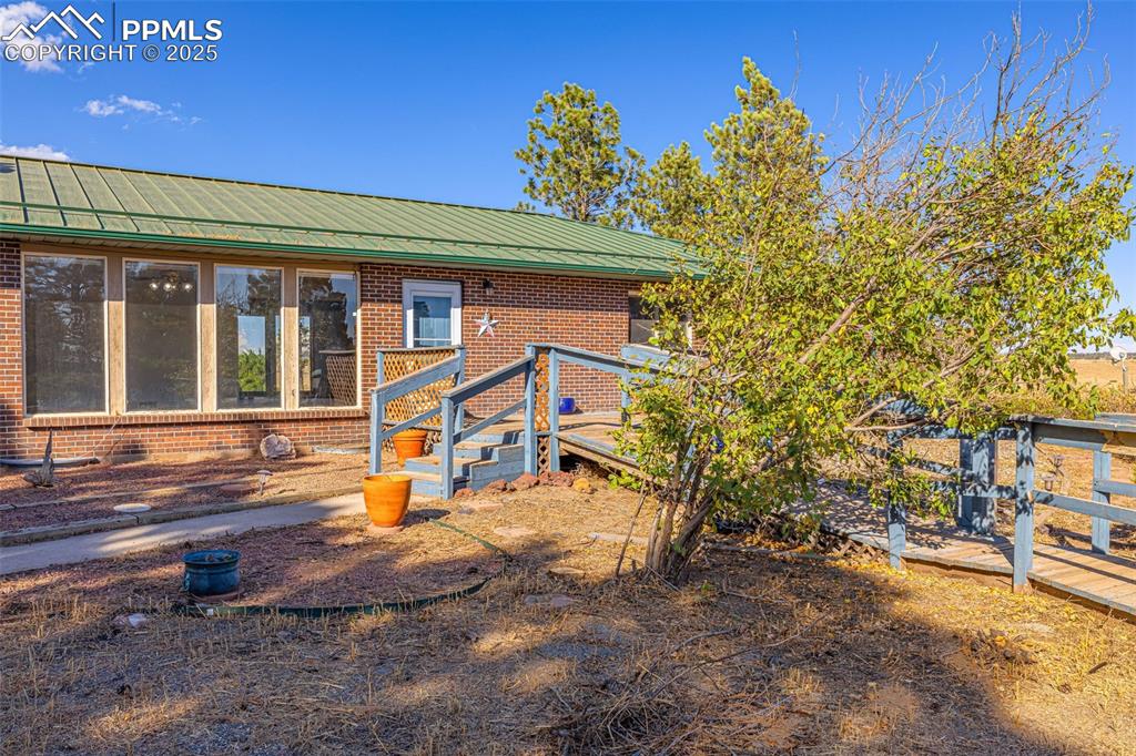 Image 4 of 42: View of front of home featuring brick siding and a metal roof