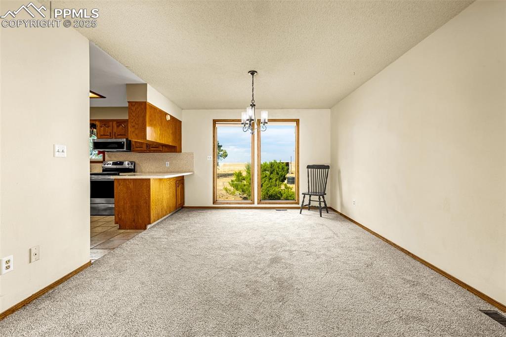 Image 9 of 42: Kitchen with brown cabinetry, backsplash, stainless steel appliances, light