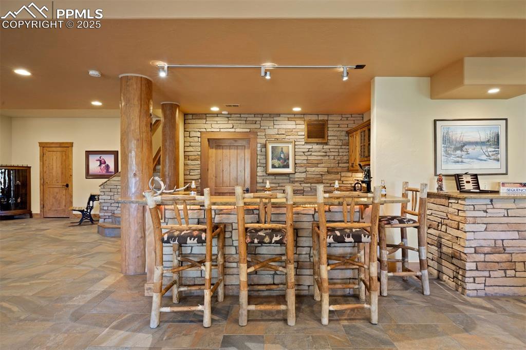 Image 20 of 41: Impressive wet bar with stone accent wall and quartzite counters.